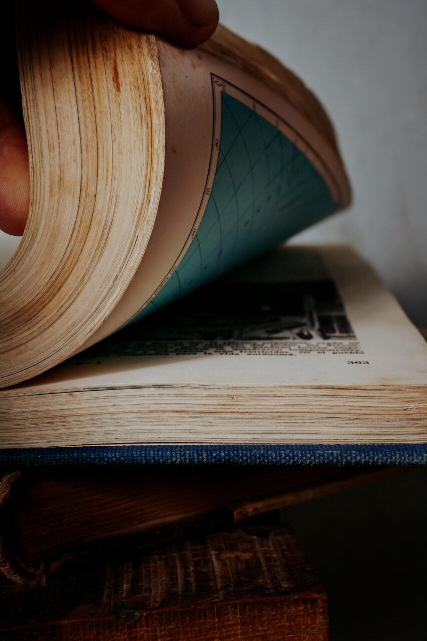 Detailed shot of a person flipping pages in a vintage book, revealing blue-tinted print.