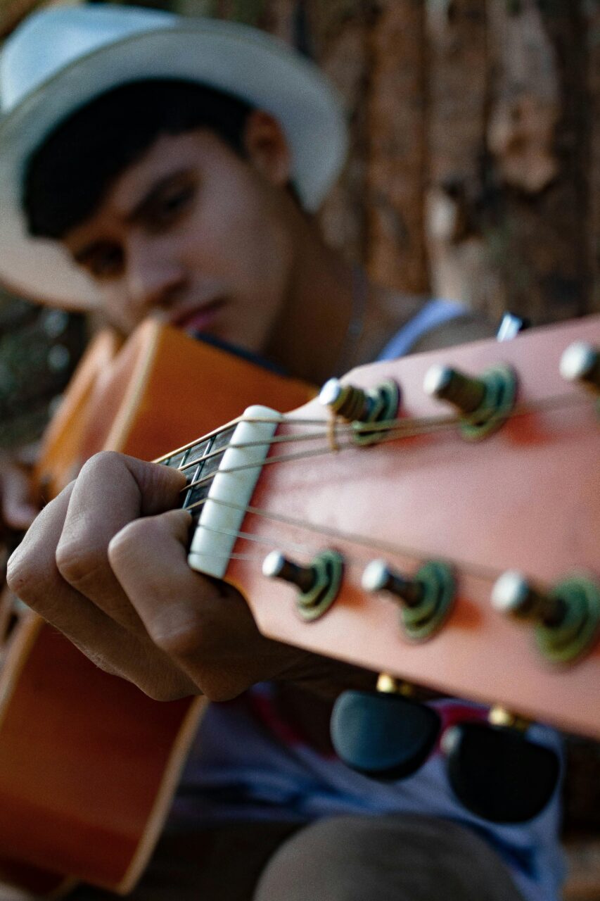 A young guitarist focuses intensely on playing an acoustic guitar.