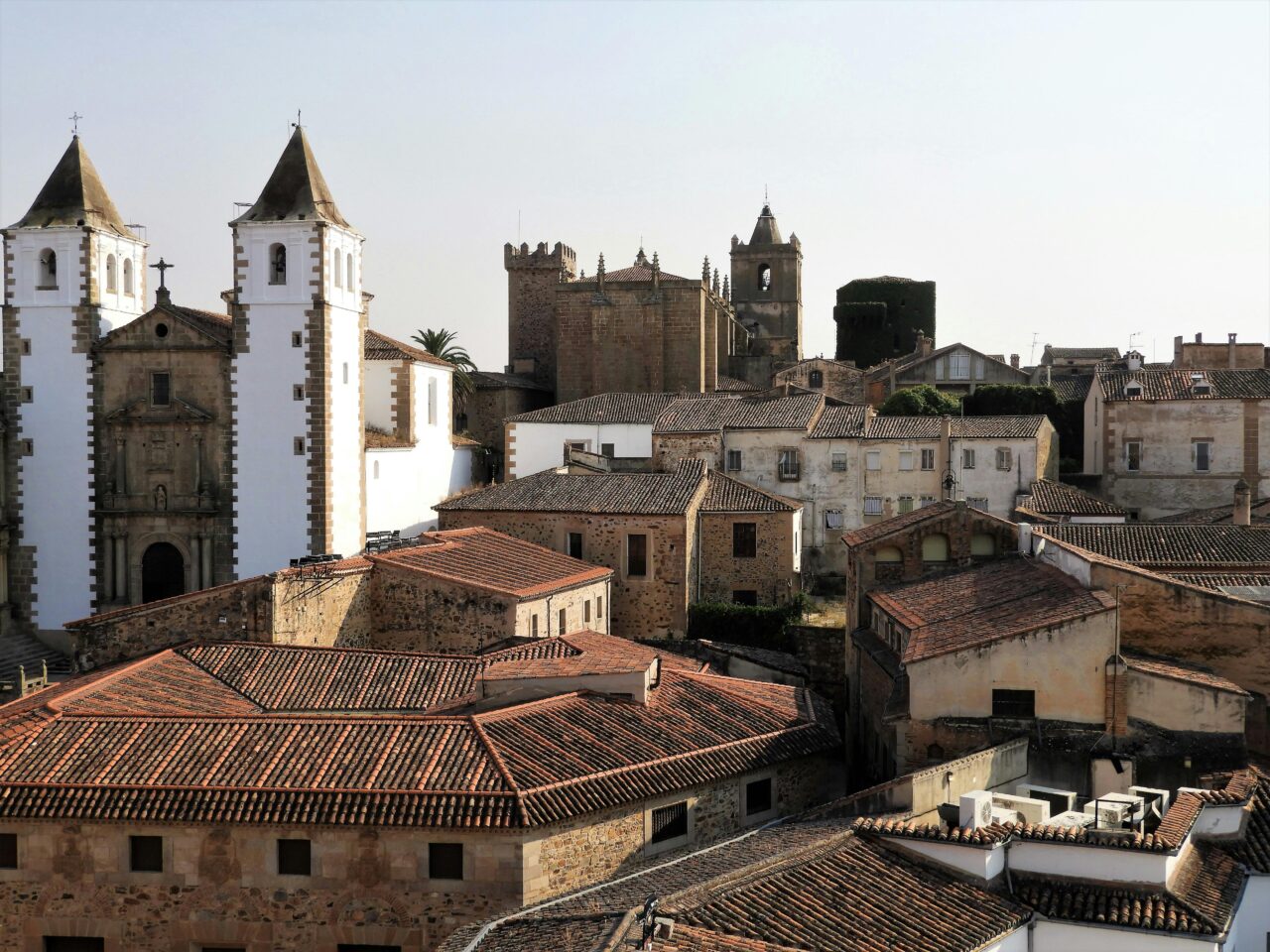 Aerial view of the historic architecture of Cáceres, Spain showcasing old stone buildings and churches.